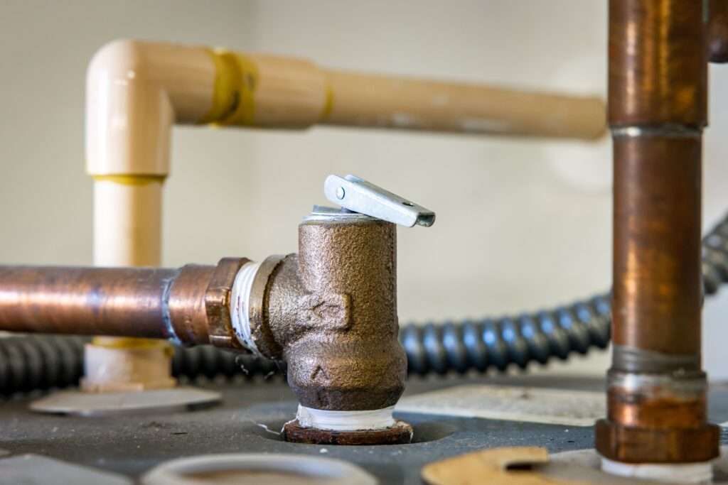 Opening the pressure relief valve on a water heater to release built-up pressure